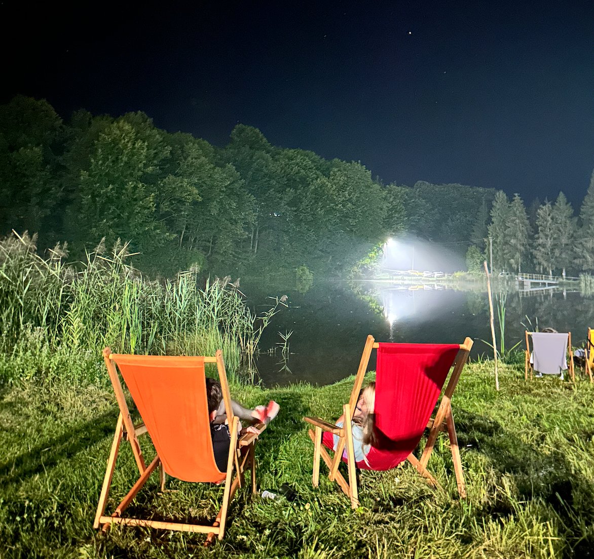 Deck chairs by the lake at night under stage lights